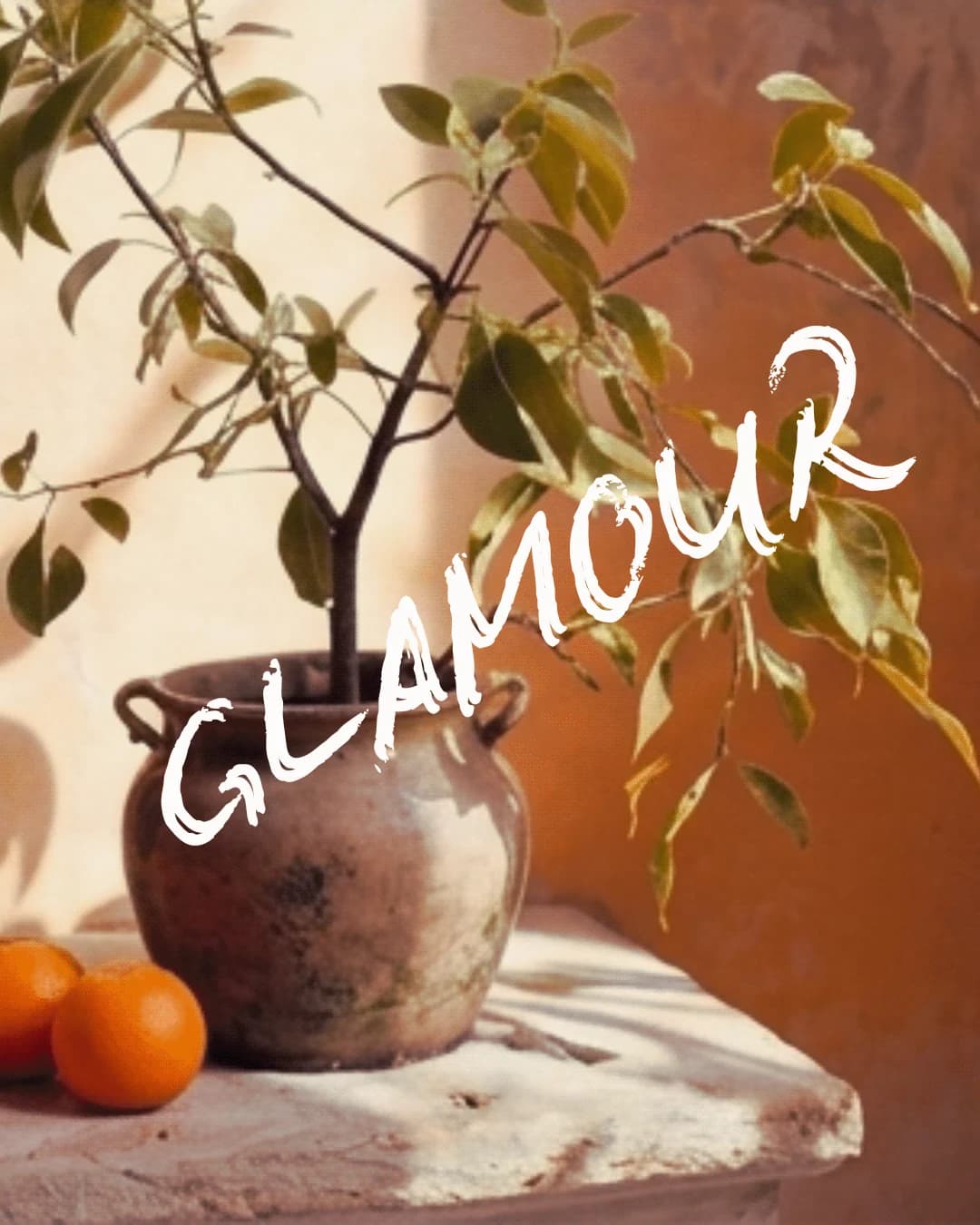 Glamour campaign frame with oranges on a stone ledge beneath the logotype